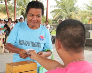A beneficiary smiles at the MLhuillier teller as she receives her cash grant.  