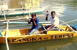 Hernando Magahom and his daughter wave their hand while aboard the 'school boat' named Bangka ni Teresa by the St. Therese’s College of Quezon City Alumnae Association. 